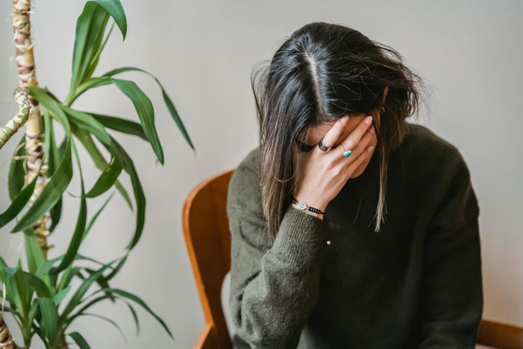 A depressed woman resting her head on her right hand.